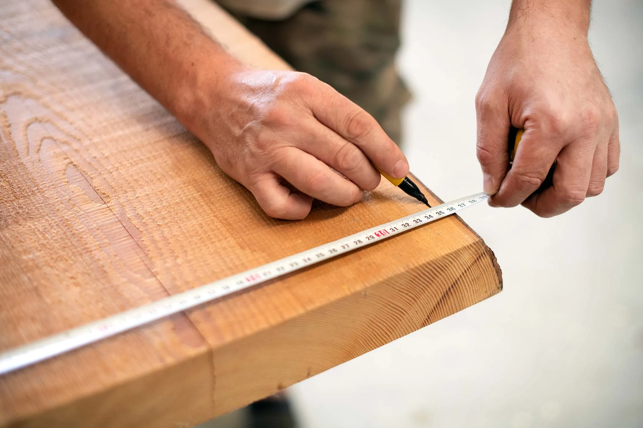 carpenter measuring a wooden plank